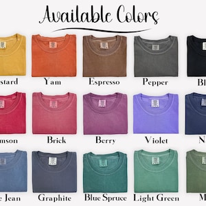 May include: A collection of fifteen crew neck t-shirts arranged in a grid, labeled Available Colors. The shirts appear in mustard, yam, espresso, pepper, black, crimson, brick, berry, violet, navy, blue jean, graphite, blue spruce, light green, and moss.