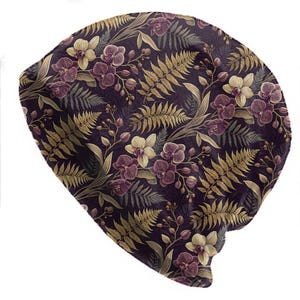 May include: A beanie hat with a floral pattern. The hat features a dark purple background with a repeating design of orchids in shades of purple and cream, along with golden fern leaves. The beanie is a soft, comfortable accessory.