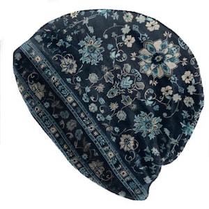 May include: A dark blue beanie hat with a floral pattern in shades of light blue and cream. The hat features a decorative border with a repeating floral and leaf design. The beanie is made of a soft, possibly velvet-like material.