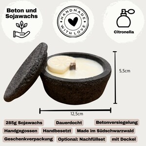 May include: A dark gray concrete candle with a lid, measuring 12.5 cm in diameter and 5.5 cm high. The candle contains soy wax and a wooden wick, and is scented with citronella. The label reads "Handmade with Love."
