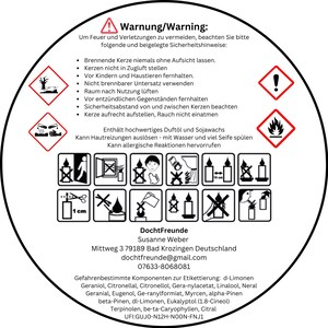 May include: A circular warning label in German with safety instructions for candles. The label includes hazard symbols, text, and a list of safety precautions. The label also contains the manufacturer's contact information and a list of ingredients.