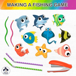 May include: A printable PDF craft activity for making a fishing game. The image shows colorful cutouts of sea creatures like a blue dolphin, a shark, a stingray, a starfish, a shrimp, and a seashell. There are also two green and purple striped straws and a red stapler.