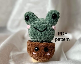 May include: A green crocheted succulent with a brown crocheted pot. The succulent has a smiling face with black eyes and pink cheeks. The pot also has a smiling face with black eyes and pink cheeks. The text "PDF pattern" is visible in the image.