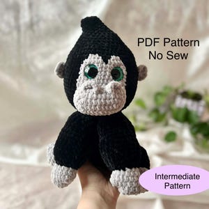 May include: A handmade, black and gray crochet gorilla plushie with large green eyes. The plushie has a gray face, hands, and feet. Text on the image reads "PDF Pattern No Sew" and "Intermediate Pattern".