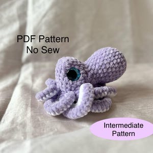 Può includere: Un piccolo polpo all'uncinetto color lavanda con grandi occhi bordati di blu. Il polpo ha otto tentacoli arricciati con dettagli bianchi. Il testo sull'immagine recita "PDF Pattern No Sew" e "Intermediate Pattern".