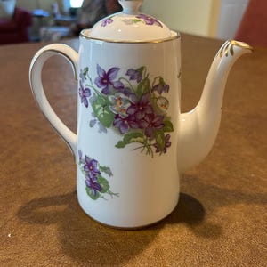 May include: A set of three ceramic mugs with a speckled, matte finish. Each mug features a different color: light blue, cream, and gray. The mugs have a simple, modern design and a comfortable handle.