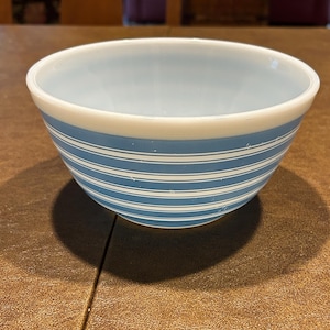 May include: A light blue and white striped mixing bowl. The bowl has a light blue interior and a white rim. The exterior features horizontal blue stripes. This vintage kitchenware is perfect for mixing ingredients.