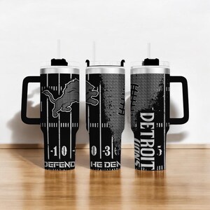 Puede incluir: Tres vasos de los Detroit Lions en blanco y negro con asas. Cada vaso presenta el logotipo del equipo, las l&iacute;neas del campo de f&uacute;tbol y las palabras "DEFEND", "THE DEN" y "DETROIT LIONS". Los vasos tienen un asa negra y una pajita blanca.