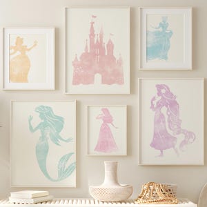 May include: A collection of framed watercolour prints depicting Disney princesses and a castle in pastel shades. The artwork includes Cinderella, Ariel, and Rapunzel. The room is decorated with a white bench, baskets, and a vase with dried plants.
