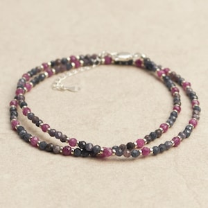 Può includere: Un delicato braccialetto a doppio filo con piccole pietre preziose sfaccettate in tonalità rosa e blu. Il braccialetto è realizzato in argento sterling e ha una chiusura a moschettone.