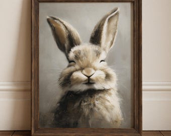Può includere: Un'opera d'arte incorniciata raffigurante un coniglio sorridente con lunghe orecchie. Il coniglio ha una pelliccia morbida e strutturata nei toni del marrone e del beige. L'opera è racchiusa in una cornice di legno marrone scuro. Lo sfondo è grigio chiaro.