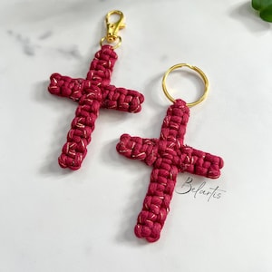 Peut inclure: Deux porte-clés en forme de croix rouge avec des accents dorés et un anneau de clé doré. Les porte-clés sont faits de cordon tressé et ont un léger éclat.