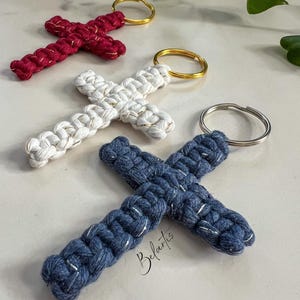 May include: Three handmade cross keychains with gold accents. The crosses are made of red, white, and blue cord. Each keychain has a metal ring.