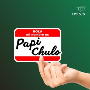 May include: A white name tag with red trim and the text "Hola mi nombre es Papi Chulo" in black.