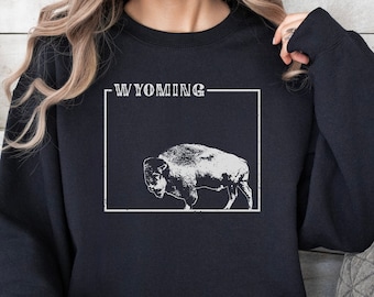 May include: Black sweatshirt with a white graphic of a buffalo and the word "WYOMING" in a white rectangle.