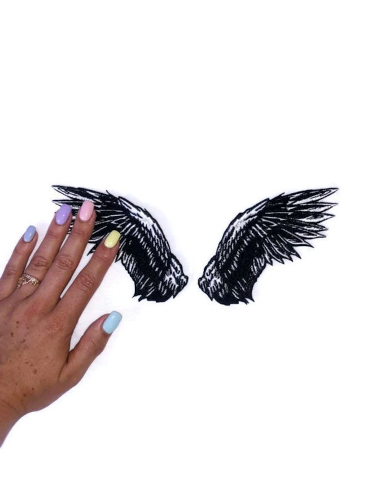 May include: A pair of black embroidered angel wings, with a detailed design, on a white background.