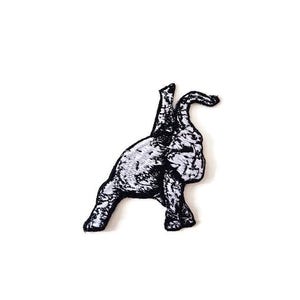 May include: A black and white embroidered patch featuring a stylized animal, possibly a dog or a rabbit, in a playful pose. The patch has a detailed, textured appearance with a black border, suitable for application on clothing or accessories.