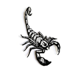 Puede incluir: Parche bordado de escorpión en blanco y negro. El escorpión está mirando hacia la derecha con la cola enroscada.