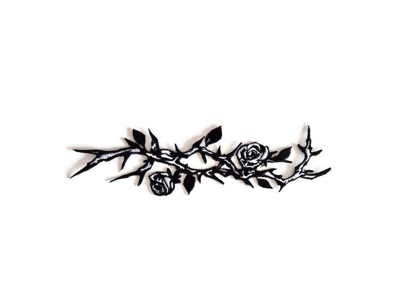 May include: A black and white embroidered patch depicting a rose branch with thorns. The design includes two roses and sharp thorns. The patch is suitable for application on clothing or accessories.
