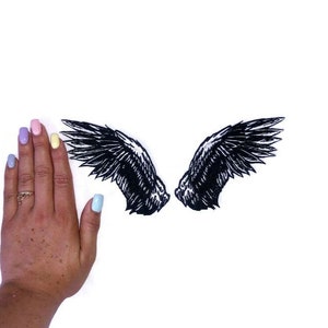 May include: A pair of black wings with a detailed design, against a white background.