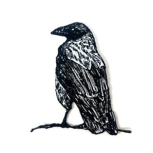 Może przedstawiać: Czarno-biała haftowana naszywka z krukiem siedzącym na gałęzi.