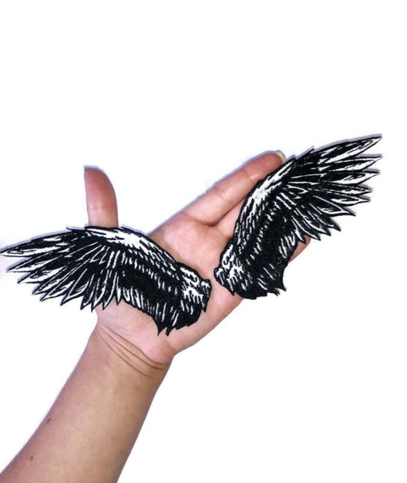 May include: Two black embroidered iron-on patches of angel wings. The wings are detailed with white stitching.