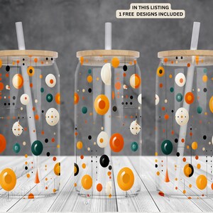 Puede incluir: Tres vasos de vidrio transparente con tapas y pajitas. Cada vaso presenta un patrón geométrico diferente de círculos y líneas naranjas, amarillas, verdes y negras.