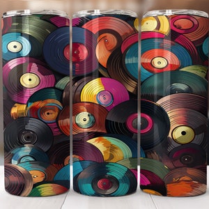 Puede incluir: Tres vasos de acero inoxidable con un diseño colorido de discos de vinilo superpuestos. Los discos son de varios tonos de rojo, naranja, amarillo, verde, azul y morado.