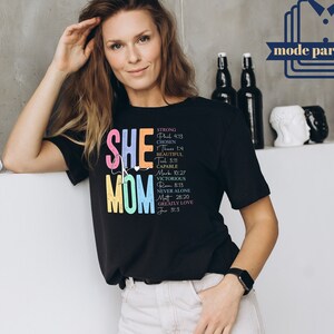 May include: Black t-shirt with a colorful graphic that says "She Mom" and includes bible verses. The graphic is in rainbow colors.