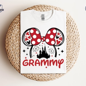 May include: White t-shirt with a red and black Mickey Mouse ears design and the word "GRAMMY" printed on the front. The ears have red polka dots and the design includes a silhouette of Cinderella's castle.