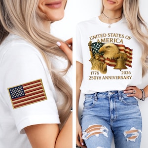 Puede incluir: Camiseta blanca con un dise&ntilde;o que celebra el 250 aniversario de los Estados Unidos de Am&eacute;rica. El dise&ntilde;o incluye un &aacute;guila, la Estatua de la Libertad, una bandera y una campana. Un parche bordado de la bandera americana est&aacute; en la manga.