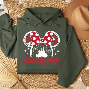 May include: A green hooded sweatshirt with a white graphic of a Mickey Mouse ear headband with a red and white polka dot bow, a white castle, and the word "GRAMMY" in red.