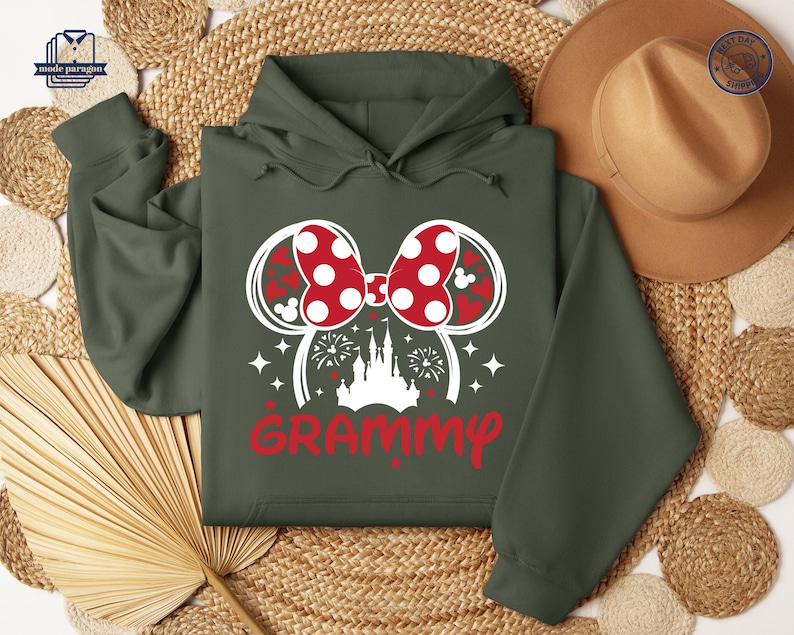 May include: A green hooded sweatshirt with a white graphic of a Mickey Mouse ear headband with a red and white polka dot bow, a white castle, and the word "GRAMMY" in red.