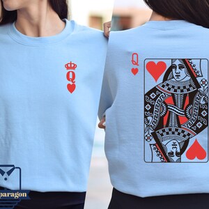 May include: A light blue sweatshirt with a Queen of Hearts playing card graphic on the back and a Queen of Hearts symbol on the front.