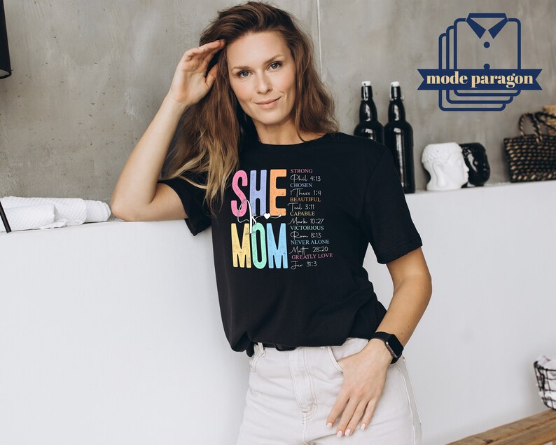 May include: Black t-shirt with a colorful graphic that says "She Mom" and includes bible verses. The graphic is in rainbow colors.