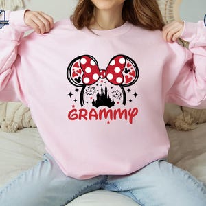 May include: Pink sweatshirt with a black and white graphic of Mickey Mouse ears with a red bow and a castle with fireworks. The text "GRAMMY" is below the graphic.