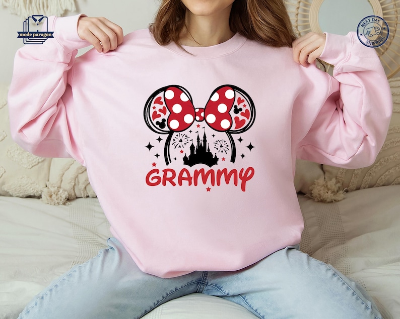 May include: Pink sweatshirt with a black and white graphic of Mickey Mouse ears with a red bow and a castle with fireworks. The text "GRAMMY" is below the graphic.