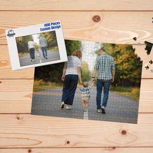 May include: A custom design 1000-piece jigsaw puzzle featuring a family walking down a path. The puzzle is partially assembled, with a smaller image of the puzzle on a white background. The image is on a wooden surface.