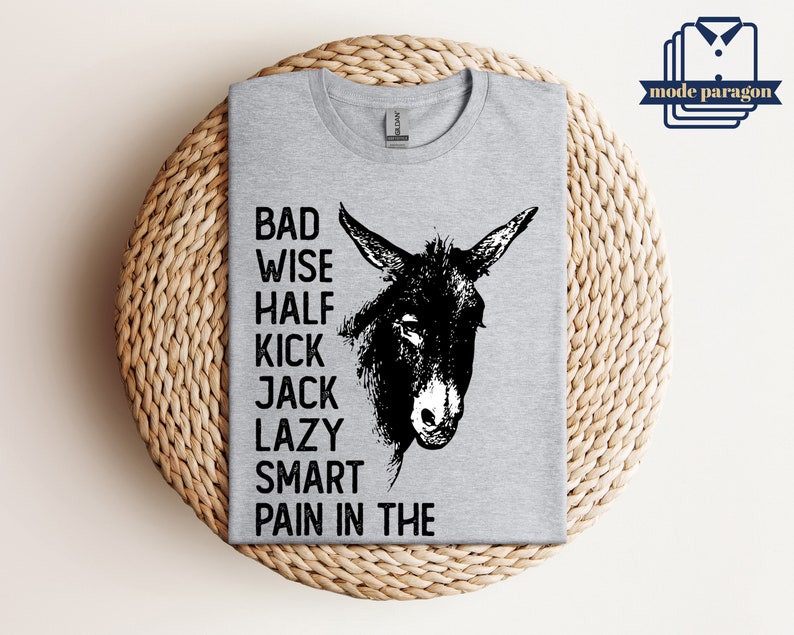 May include: Gray t-shirt with a black and white illustration of a donkey's head. The text "Bad Wise Half Kick Jack Lazy Smart Pain in the" is printed on the shirt.