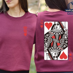 May include: A maroon t-shirt with a red queen of hearts playing card design on the back. The front of the shirt has a small red queen of hearts symbol.