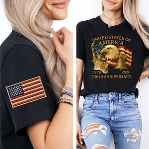 Puede incluir: Camiseta negra con un parche de la bandera estadounidense en la manga. La otra camiseta tiene un gr&aacute;fico de un &aacute;guila, la Estatua de la Libertad y una bandera ondeando con el texto "UNITED STATES OF AMERICA 1776 2026 250TH ANNIVERSARY."
