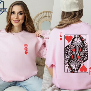 May include: Pink sweatshirt with a red queen of hearts playing card graphic on the back and a small red queen of hearts graphic on the front.