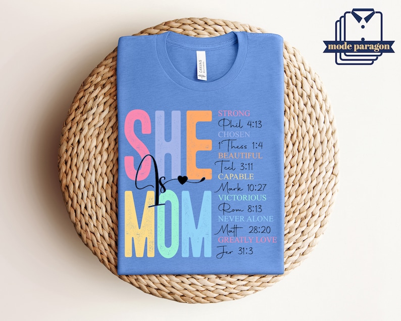May include: A light blue t-shirt with the text "She is Mom" in rainbow colors. The text is surrounded by bible verses about strength, love, and being chosen.
