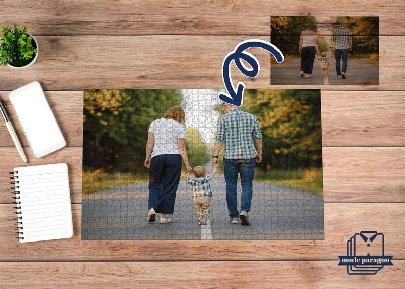 May include: A family walking on a paved path, captured in a jigsaw puzzle. The puzzle shows a couple and a child holding hands, with a blurred background of trees. The puzzle is on a wooden surface, with a small plant, a phone, and a notepad.