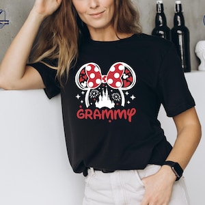 May include: Black t-shirt with a white graphic of a red and white Minnie Mouse bow with a castle and fireworks in the center. The text "GRAMMY" is below the graphic.