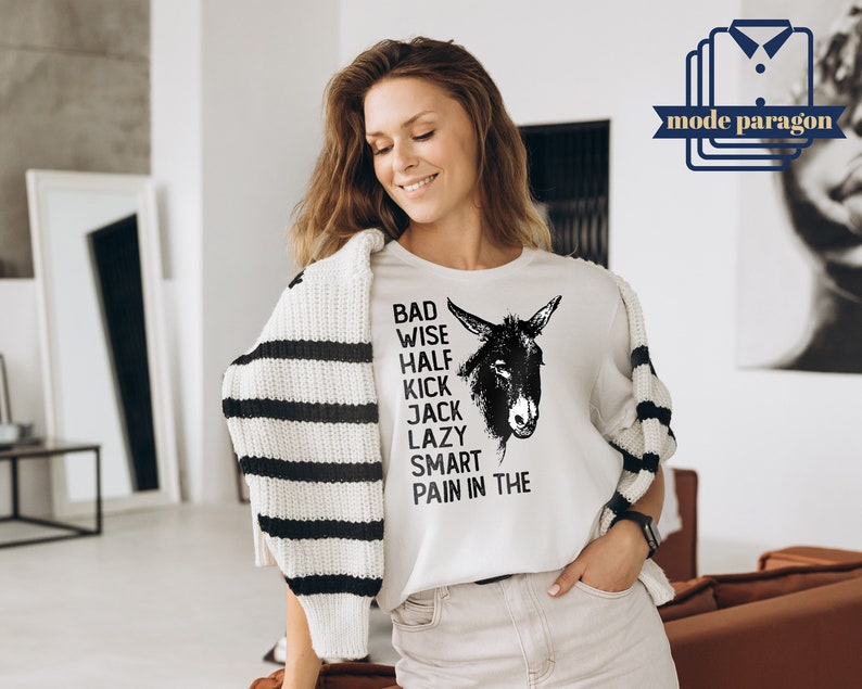 May include: White t-shirt with a black and white illustration of a donkey and the text "Bad Wise Half Kick Jack Lazy Smart Pain in the".