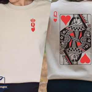 May include: Two cream colored sweatshirts with a red queen of hearts playing card design. One sweatshirt has a simple red queen of hearts symbol with a crown. The other sweatshirt has a full playing card design with a queen of hearts and the text "Q" on the card.