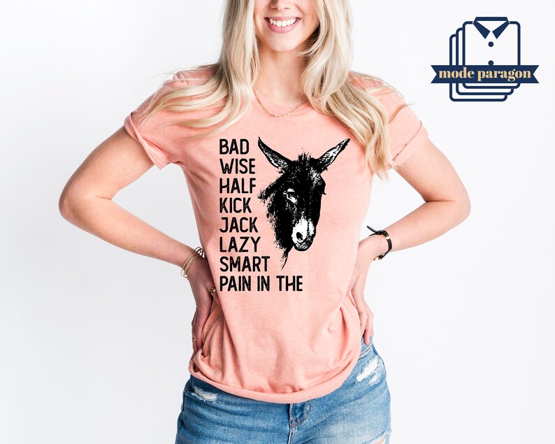 May include: A peach colored t-shirt with a black donkey illustration and the text "Bad Wise Half Kick Jack Lazy Smart Pain in the" printed on the front.