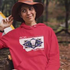 May include: Red hooded sweatshirt with a white outline of the state of Montana and a graphic of a skull with feathers. The text "406 WHERE MY STORY BEGAN" is printed above the graphic and "MONTANA" is printed below.