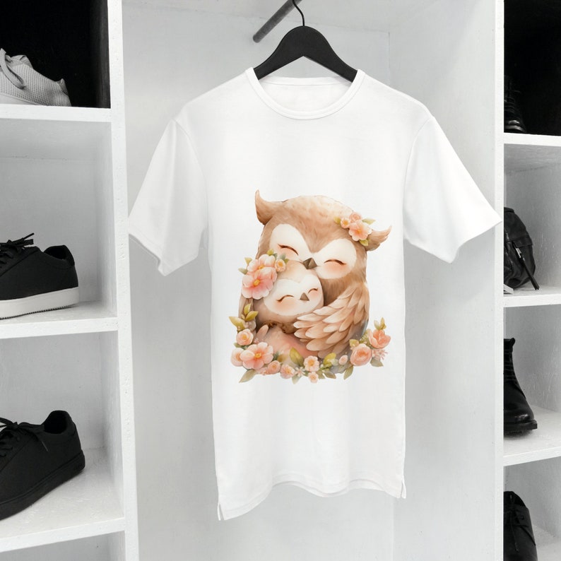 May include: White t-shirt with a graphic of two owls hugging each other. The owls are brown and have pink flowers around them.